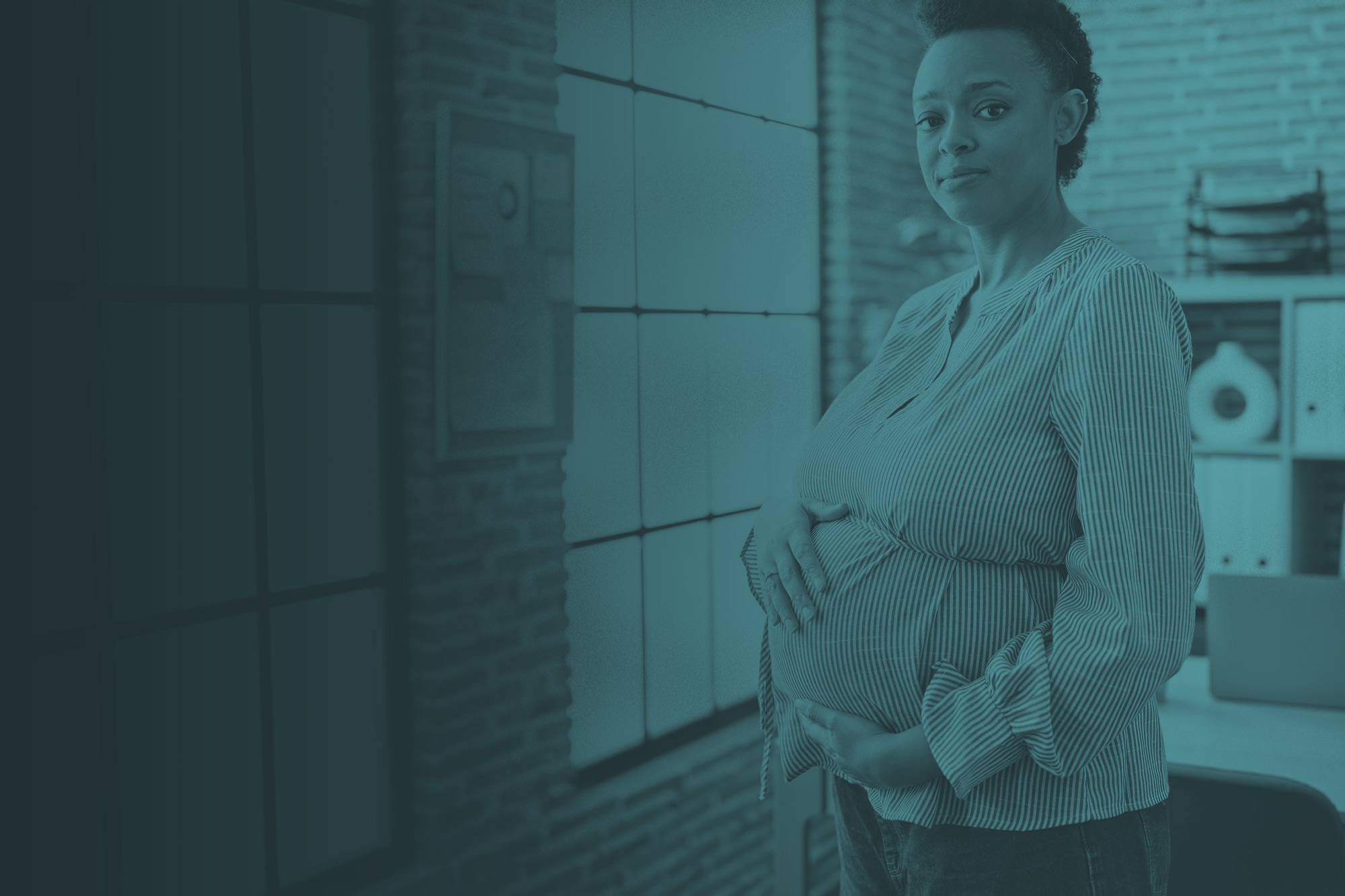 pregnant woman standing near window holding her belly