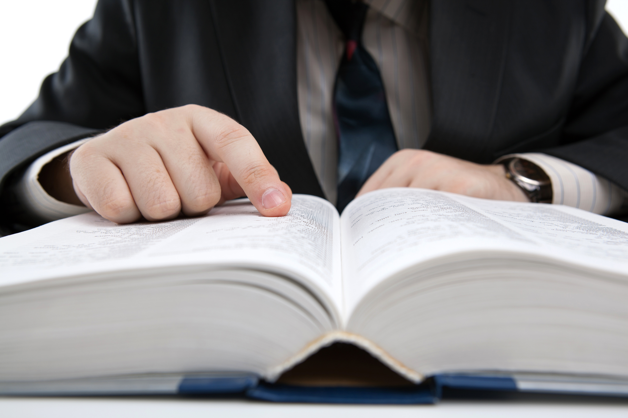 Man reads through large employee handbook in office.