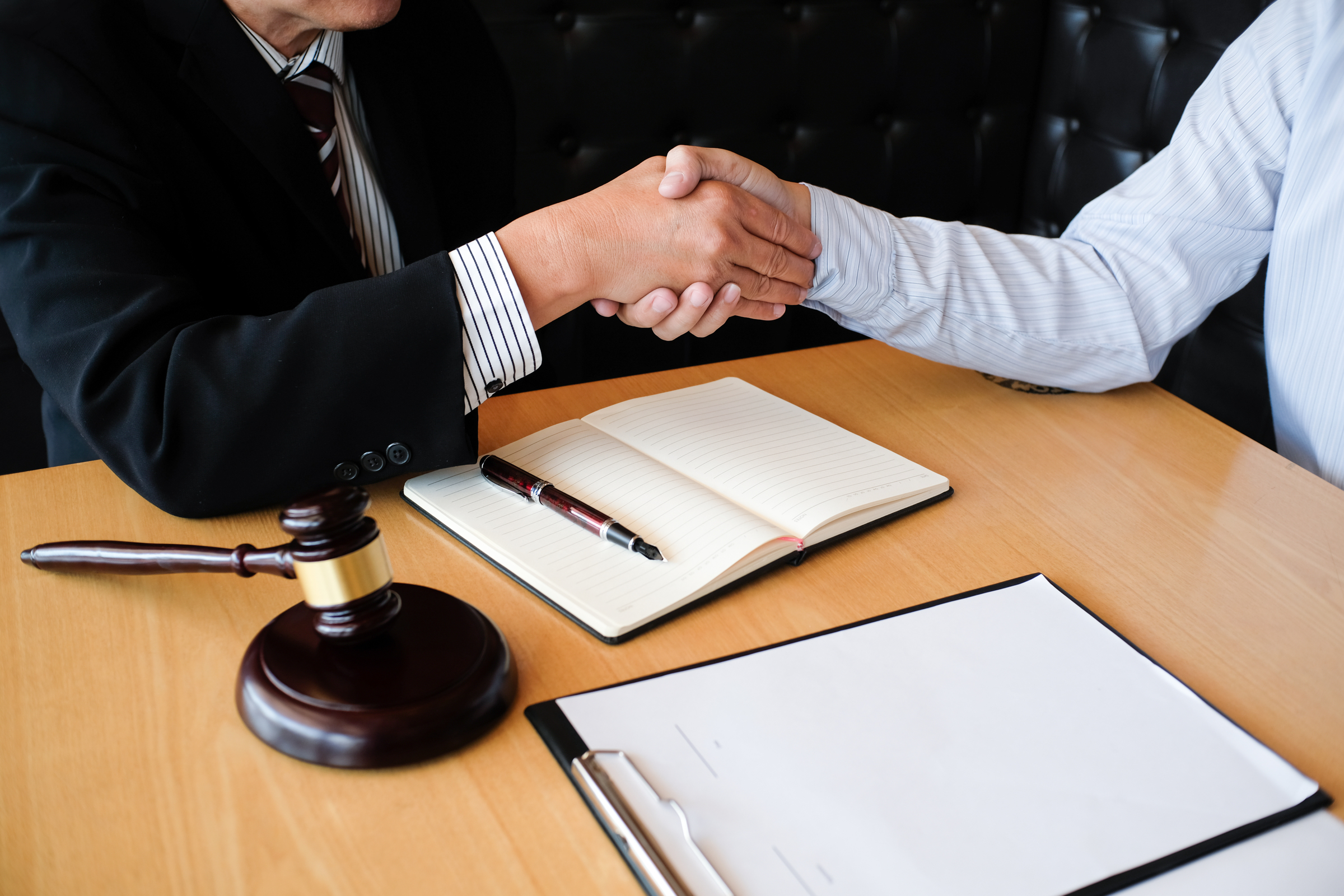 An employment discrimination lawyer shakes hands with his client after winning a discrimination case based on the client's criminal record.