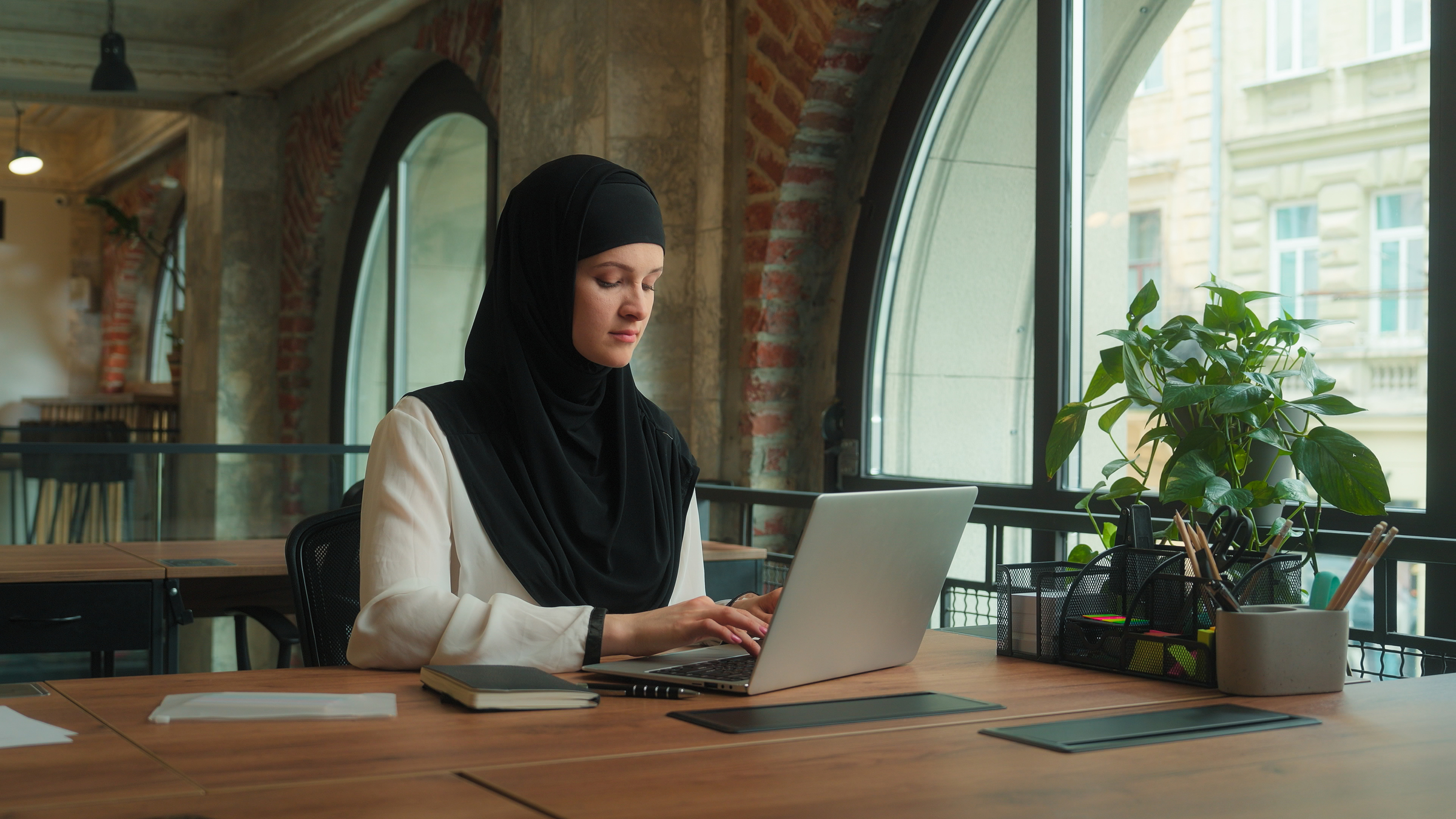 A Muslim woman works in a New York City office space, her rights to a discrimination-free workplace guaranteed by local, state, and federal laws.